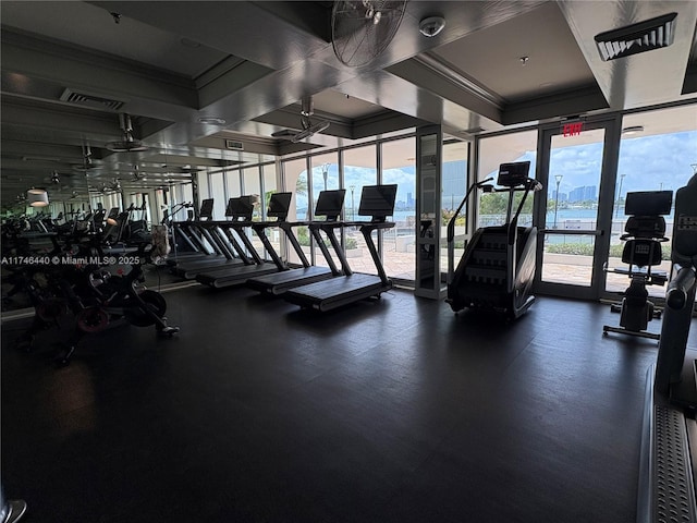 exercise room with a water view, expansive windows, and ornamental molding