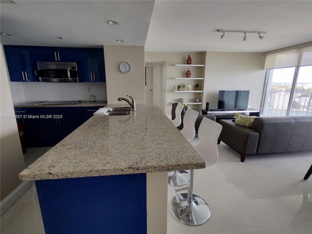 kitchen with blue cabinets, sink, a breakfast bar area, a center island with sink, and black electric cooktop