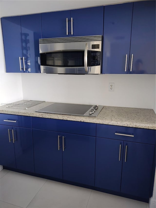 kitchen with black electric stovetop and blue cabinets