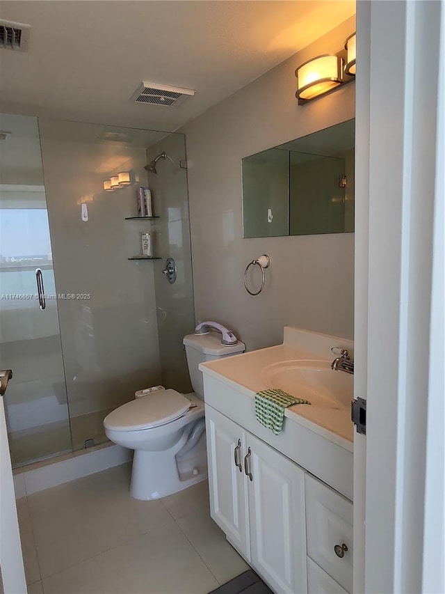 bathroom featuring tile patterned floors, vanity, toilet, and a shower with shower door