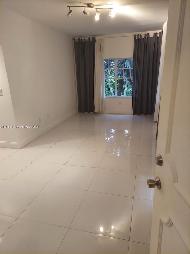 unfurnished room with track lighting and tile patterned floors