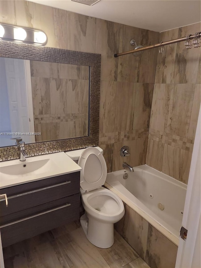 full bathroom with toilet, tiled shower / bath, tile walls, vanity, and hardwood / wood-style floors