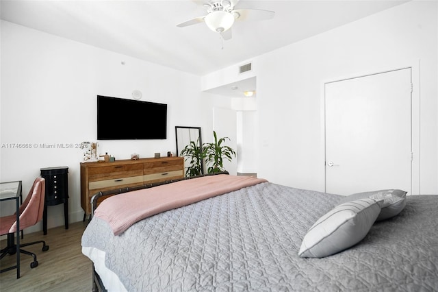 bedroom with ceiling fan, visible vents, and wood finished floors