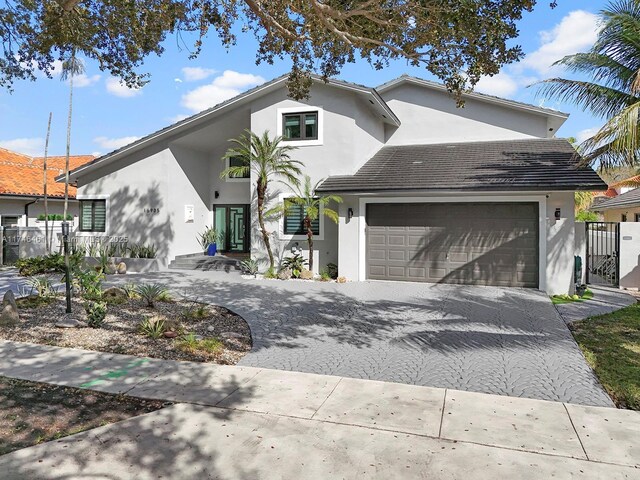 view of front of home featuring a gate, decorative driveway, fence, and stucco siding