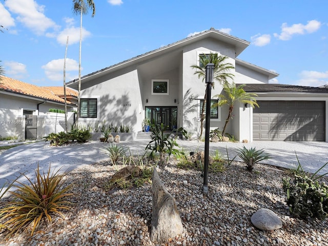 view of front of home with a garage, driveway, fence, and stucco siding