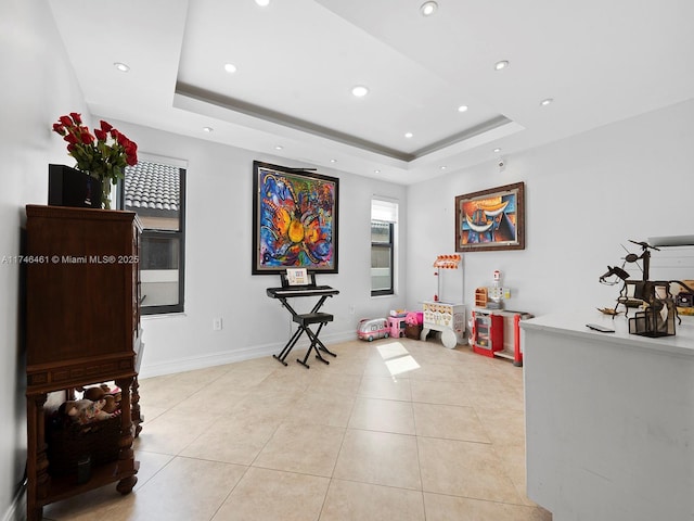 rec room featuring a tray ceiling and light tile patterned floors