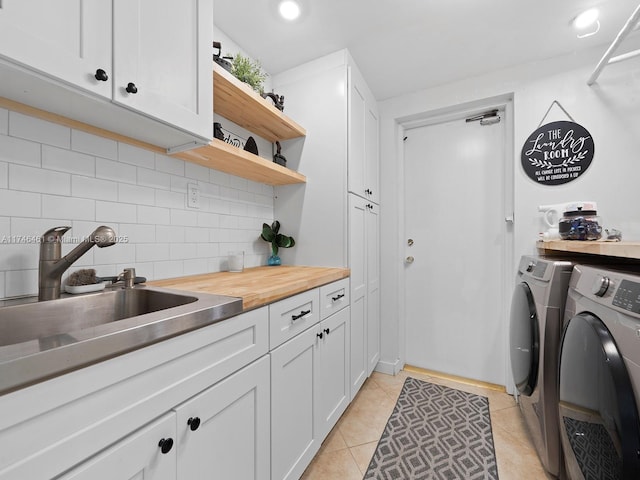 laundry area with washer and dryer, cabinets, sink, and light tile patterned flooring