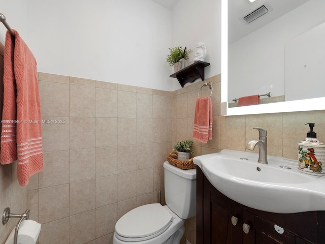 bathroom with vanity, tile walls, and toilet