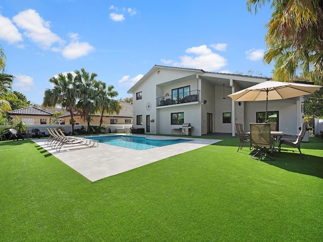 rear view of house featuring a patio, a yard, a balcony, and a fenced in pool