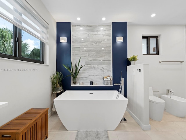 bathroom with tile patterned flooring, toilet, a bathing tub, and a bidet