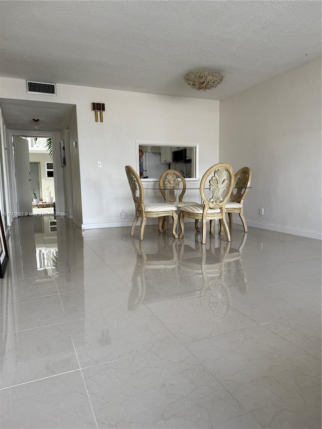 dining room with a textured ceiling, marble finish floor, visible vents, and baseboards