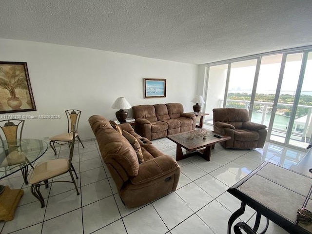 living room with light tile patterned floors, a textured ceiling, and a wall of windows