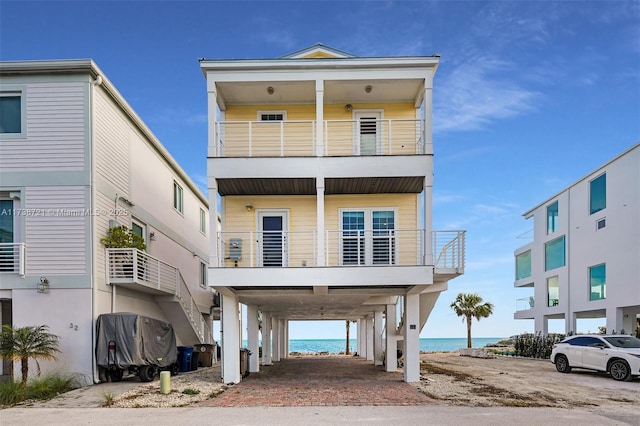 view of front facade with a carport, a balcony, and a water view