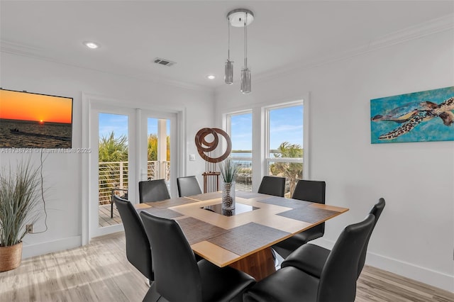 dining area featuring plenty of natural light, ornamental molding, and light wood-type flooring