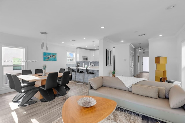 living room with sink, ornamental molding, and light hardwood / wood-style floors