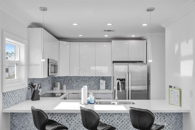 kitchen featuring appliances with stainless steel finishes, decorative light fixtures, kitchen peninsula, and white cabinets