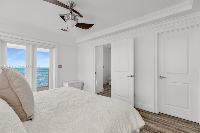 bedroom featuring ceiling fan, access to exterior, a water view, wood-type flooring, and ornamental molding