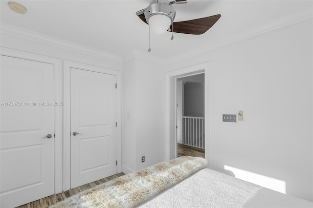 bedroom with ceiling fan, ornamental molding, and wood-type flooring