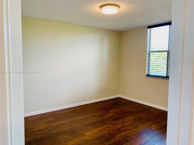 empty room featuring dark wood-type flooring and a textured ceiling