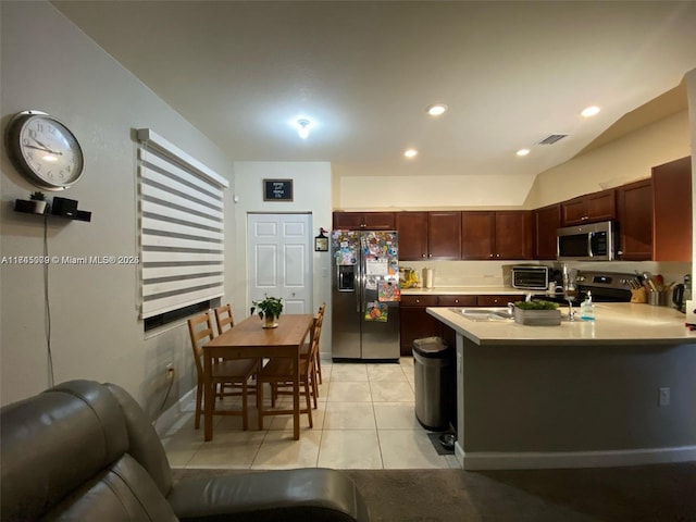 kitchen with appliances with stainless steel finishes, lofted ceiling, and light tile patterned floors