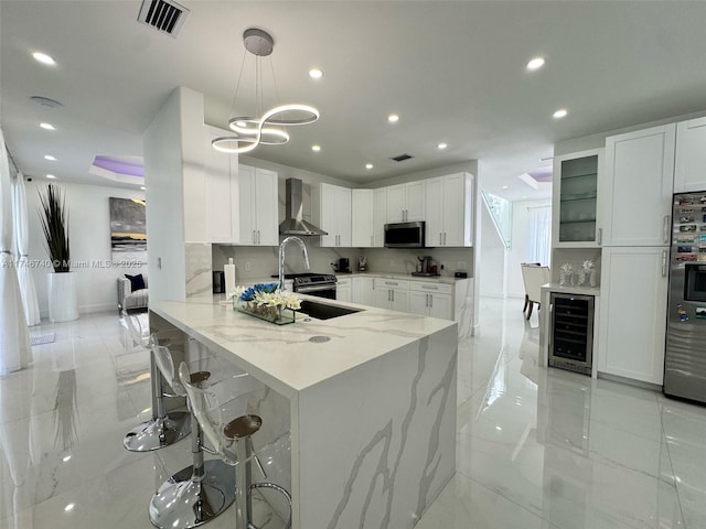 kitchen featuring appliances with stainless steel finishes, wall chimney range hood, and white cabinets