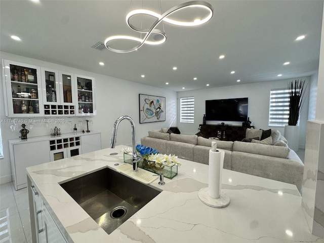 kitchen featuring white cabinetry, sink, decorative light fixtures, and light stone countertops