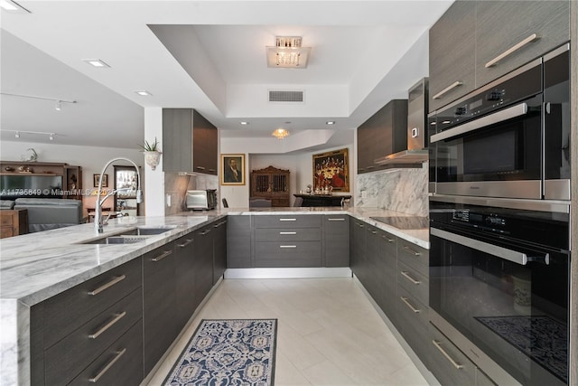 kitchen featuring tasteful backsplash, sink, light stone counters, kitchen peninsula, and stainless steel double oven