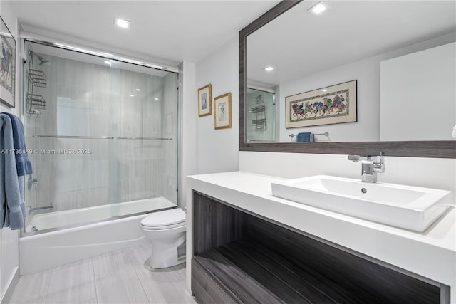 full bathroom with vanity, enclosed tub / shower combo, and toilet