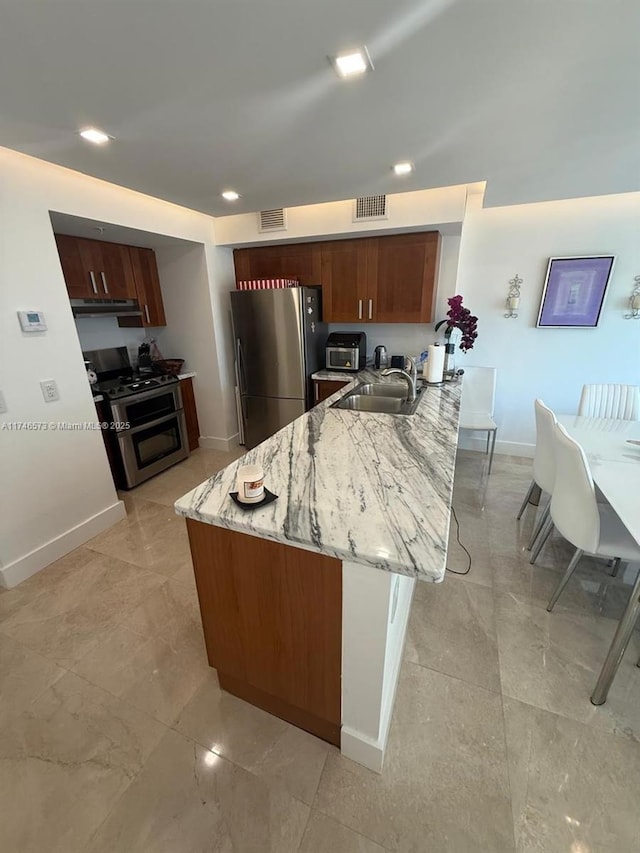 kitchen featuring sink, light stone countertops, kitchen peninsula, and appliances with stainless steel finishes