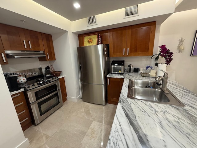 kitchen featuring stainless steel appliances, light stone countertops, and sink