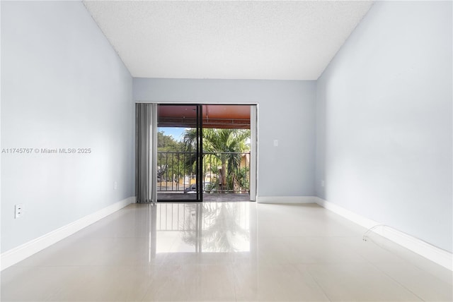 tiled empty room featuring baseboards and a textured ceiling