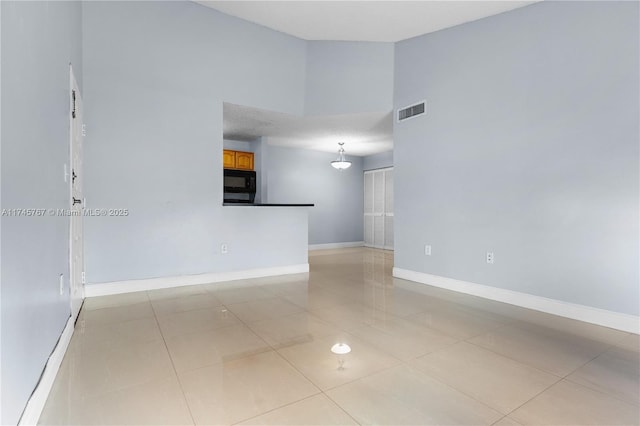 spare room featuring high vaulted ceiling, light tile patterned flooring, visible vents, and baseboards