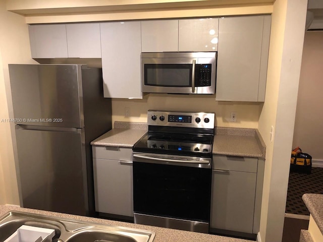 kitchen featuring appliances with stainless steel finishes, sink, and gray cabinetry