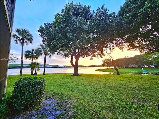 surrounding community with a water view and a lawn