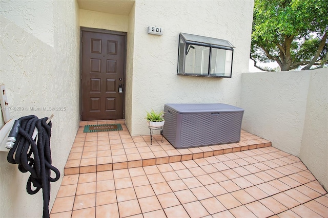 entrance to property with a patio area, fence, and stucco siding