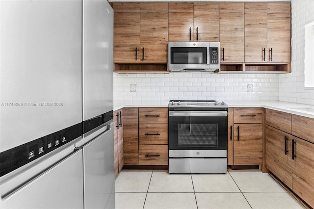 kitchen featuring light tile patterned floors, open shelves, light countertops, appliances with stainless steel finishes, and brown cabinetry