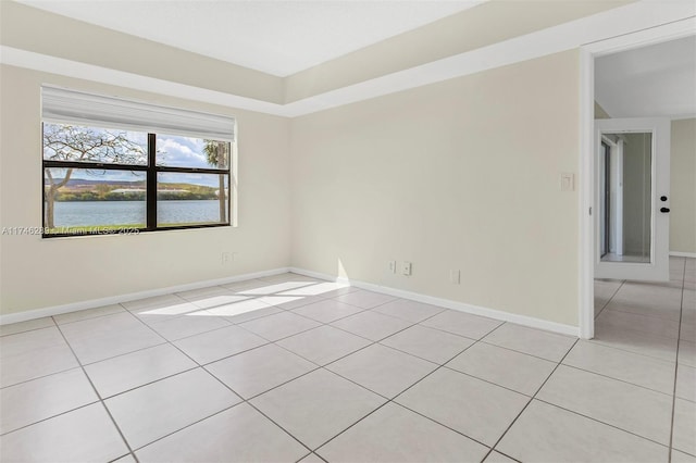 unfurnished room featuring a water view, baseboards, and light tile patterned floors