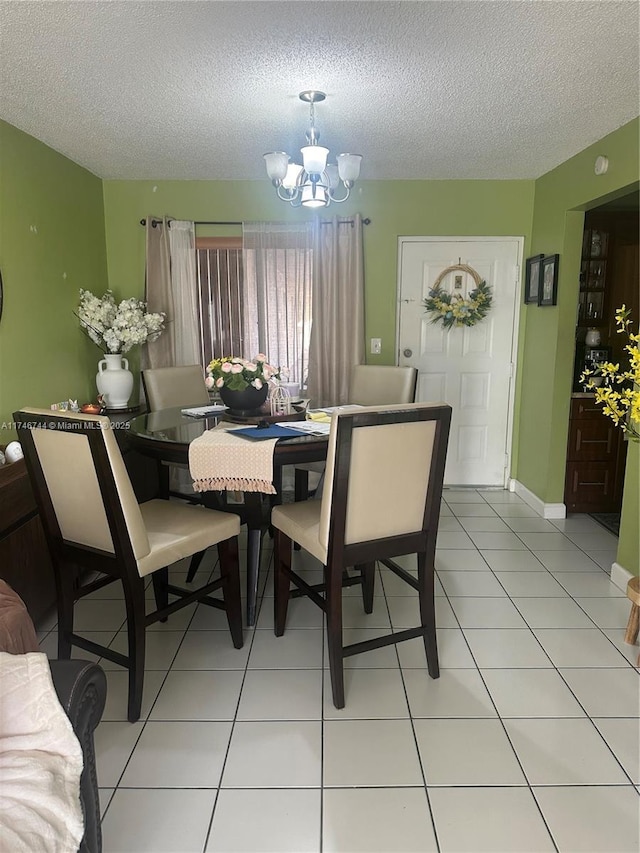 dining space with an inviting chandelier, a textured ceiling, and light tile patterned floors