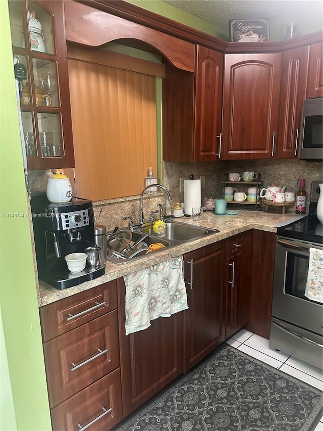 kitchen with light tile patterned floors, sink, stainless steel appliances, and backsplash