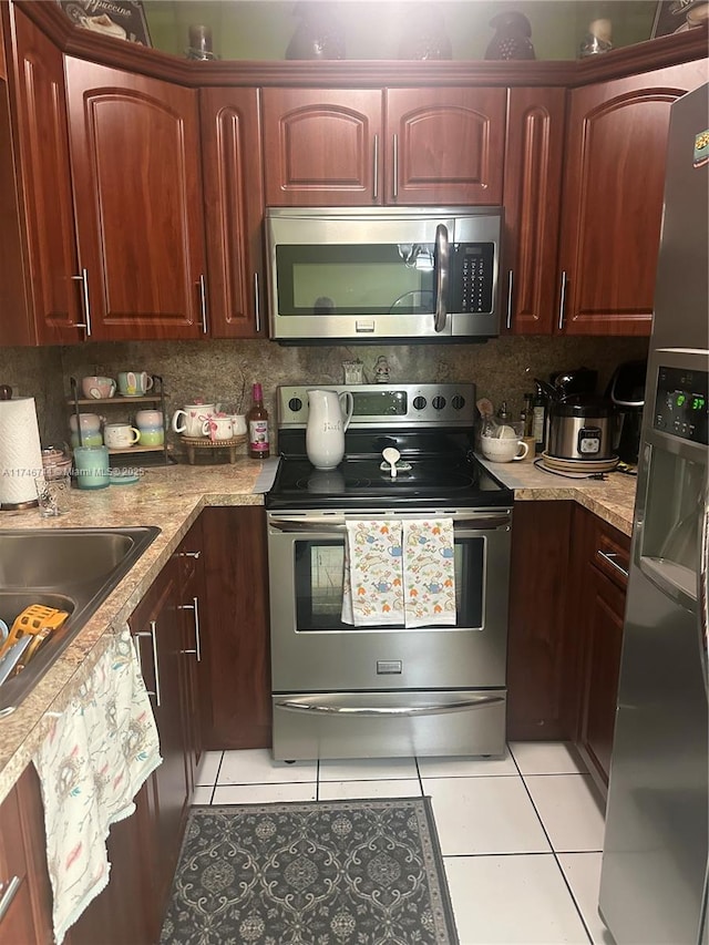 kitchen featuring appliances with stainless steel finishes, tasteful backsplash, light stone counters, and light tile patterned floors