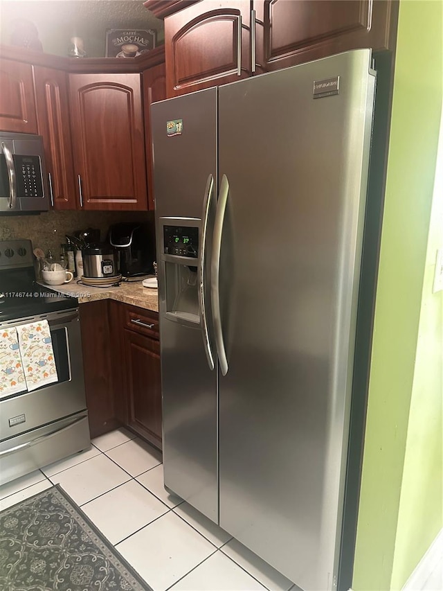 kitchen featuring appliances with stainless steel finishes, light tile patterned floors, light stone countertops, and decorative backsplash