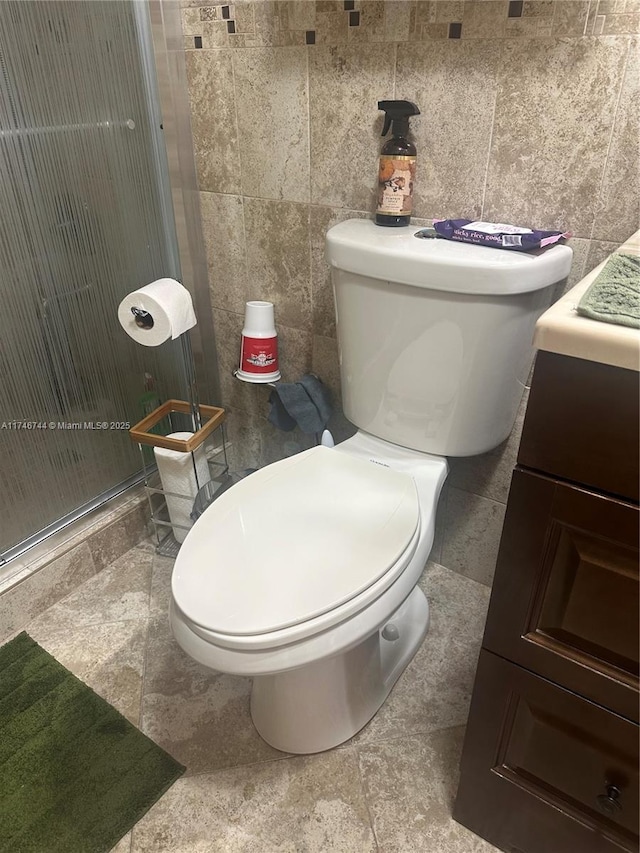 bathroom with tile walls, vanity, an enclosed shower, and toilet