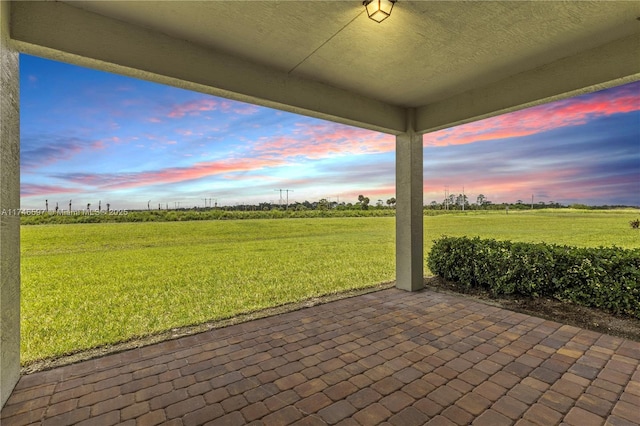 patio terrace at dusk with a yard and a rural view