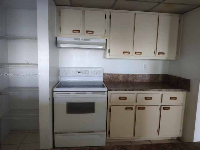 kitchen featuring light tile patterned floors, white cabinets, and white range with electric cooktop