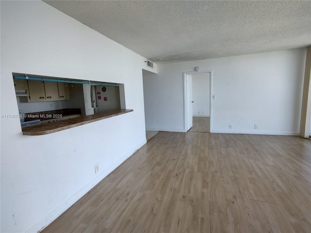 unfurnished living room featuring light hardwood / wood-style floors and a textured ceiling