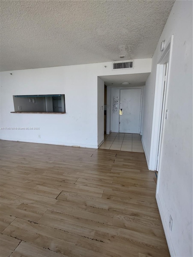 spare room featuring a textured ceiling and light wood-type flooring