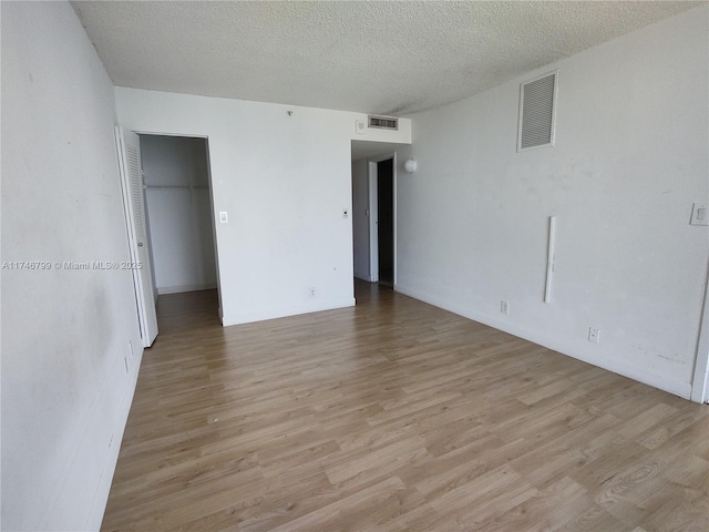 empty room with a textured ceiling and light wood-type flooring