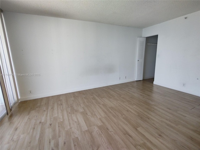 empty room with light hardwood / wood-style flooring and a textured ceiling