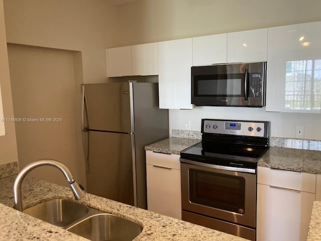 kitchen featuring light stone counters, sink, white cabinets, and appliances with stainless steel finishes