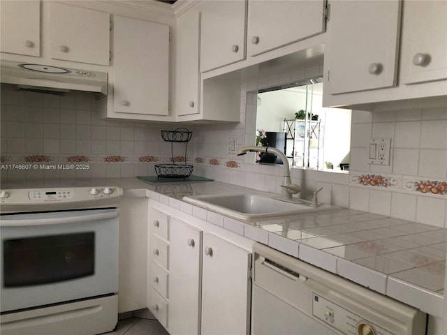 kitchen with white appliances, white cabinets, backsplash, under cabinet range hood, and a sink